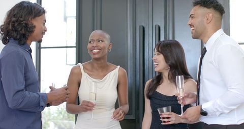 Diverse adults laughing and networking at elegant daytime cocktail reception with drinks