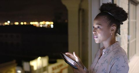 Businesswoman Checking Tablet at Night in Urban Environment