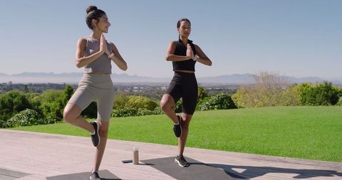 Two Diverse Women Practicing Yoga Tree Pose Outdoors on Deck