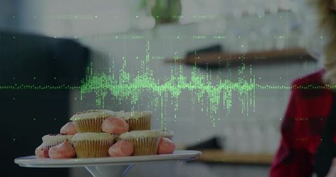 Pink frosted cupcakes on white pedestal with digital wave overlay in modern kitchen