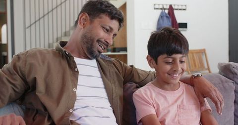 Father and son enjoying time together on sofa in cozy home