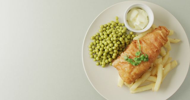 Image of fish, chips and peas on plate with dip, with copy space on white background. Tasty hot homemade fast food meal.