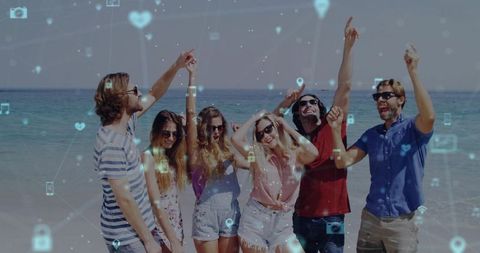 Friends celebrating on beach pointing and dancing with social media network overlay