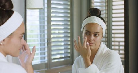 Young Woman Applying Skincare Cream in Home Bathroom