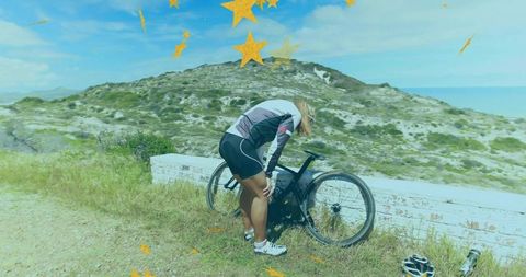 Female cyclist adjusting bicycle on coastal path for adventure ride
