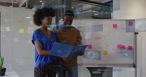 Collaborative team reviewing project folder and whiteboard brainstorming in modern office
