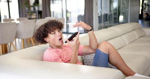 Young Man Using Smartphone for Voice Communication in Modern Living Room