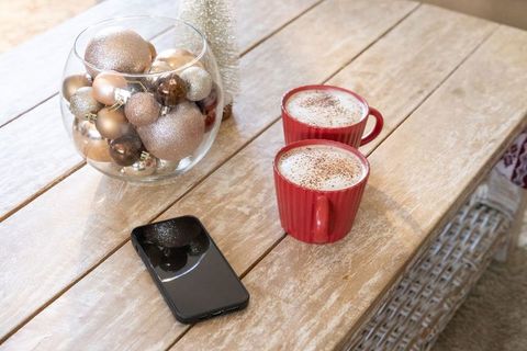 Sharing cozy cocoa on rustic coffee table with red mugs and glittering ornaments