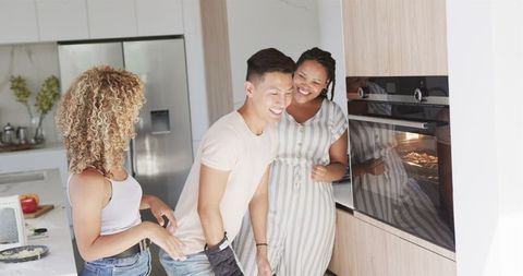 Young Friends Sharing a Laugh While Cooking in Modern Kitchen