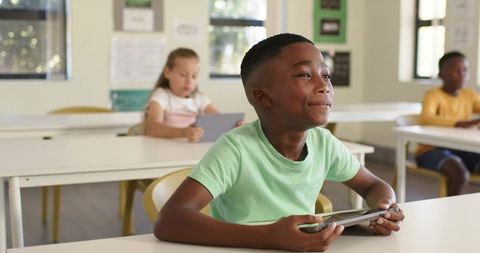 Diverse elementary students using tablets in bright classroom engaging in digital learning