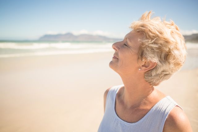 Close up of smiling senior woman with eyes closed standing at beach