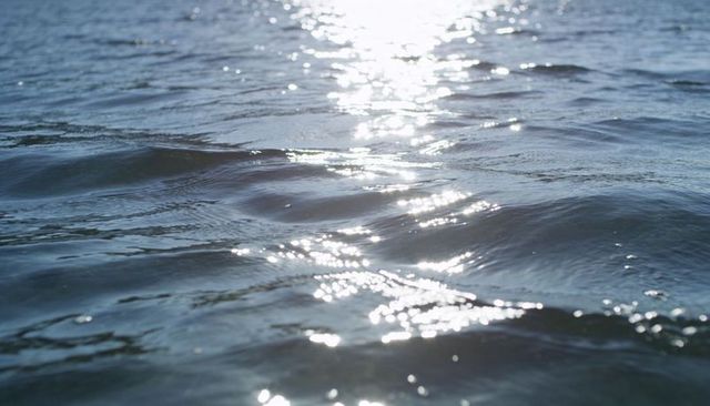 Shimmering sunlight dancing on ocean surface with gentle ripples and reflective bokeh glow