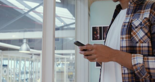 Young Man Using Smartphone While Standing Near Window - Download Free Stock Images Pikwizard.com