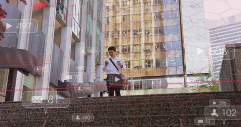 Asian businessman checking smartphone on urban steps holding coffee and messenger bag