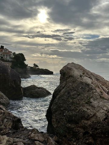 Dramatic coastal beach landscape at sunset with rocky shoreline