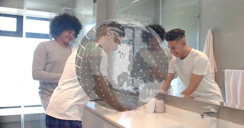 Young men washing hands at modern bathroom vanity with mirror reflection and globe overlay