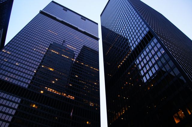 Skyscrapers towering into the sky during dusk, illuminated with office lights. Perfect for corporate brochures, financial reports, city lifestyle promotions, and architectural portfolios.