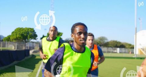 Youth soccer players sprinting in neon training vests during team drill on grass pitch