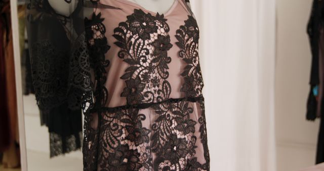 Elegant black lace dress draping on mannequin in a chic boutique showroom, showcasing finely crafted details and intricate lacework. Ideal for use in fashion editorials, boutique marketing, social media posts for high-end fashion brands, and online store listings.