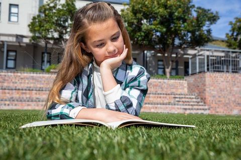 Little Girl Reading Book on Sunny Day in Campus Garden