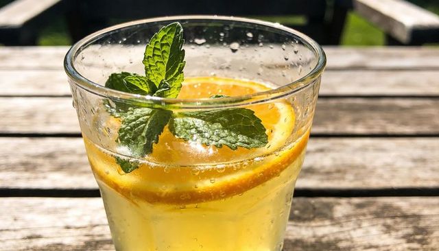 Sunlit citrus mint sparkling beverage on wooden patio table, refreshing summer cold drink