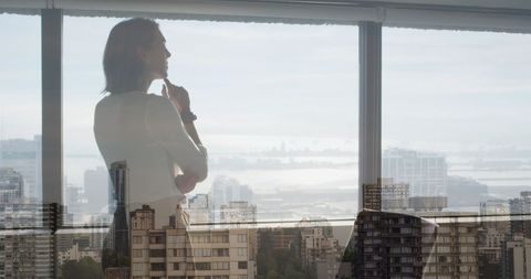 pensive businesswoman overlooking urban skyline in office - Download Free Stock Images Pikwizard.com