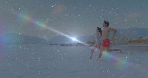 Couple running on beach at twilight with starry lens flare, romantic shoreline sprint