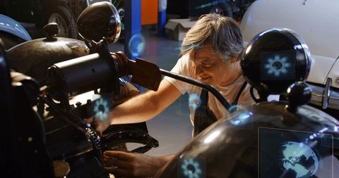 Experienced mechanic diagnosing motorcycle with augmented reality diagnostics in garage
