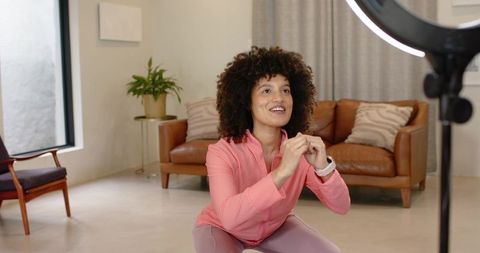 Home workout instructor streaming live squat tutorial with ring light smartwatch