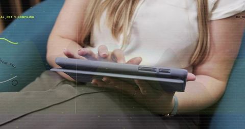 Woman tapping tablet on lap in casual office lounge with wristband and charging cable