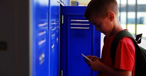 Schoolboy Engaged with Smartphone at School Lockers