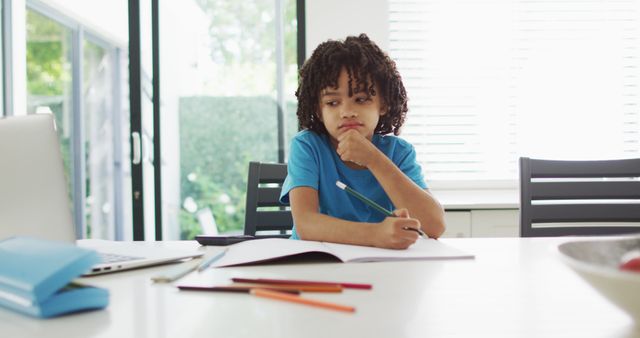 Young boy sitting at a clean, modern table, deeply focused on his homework. This image can be used in educational content, parenting blogs, school promotional material, and advertisements for educational products or services.