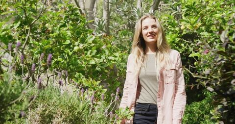 Smiling Woman Enjoying a Sunny Garden Stroll