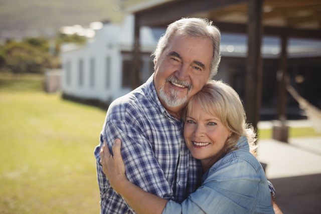 Senior couple smiling and embracing in a garden, showcasing love and togetherness. Ideal for use in advertisements, retirement planning brochures, family and lifestyle blogs, and healthcare promotions.