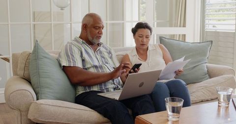 Senior couple managing finances at home in living room