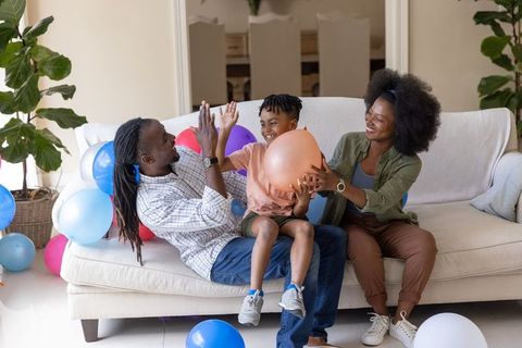 African american family celebrating with balloons at home, parents playing with son