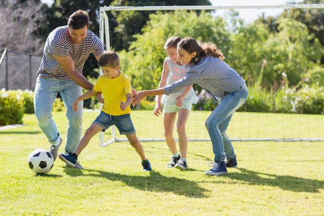 Family enjoying a sunny day outdoors, playing football in a park. Great for themes around family bonding, outdoor activities, and promoting a healthy lifestyle. Ideal for use in advertisements, brochures, and blog articles about family fun, sports, and well-being.