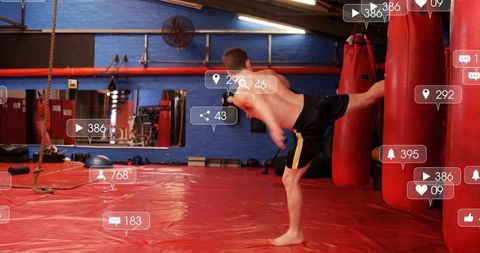 Teenage Boy Training with Martial Arts Kicking Heavy Bag in Gym