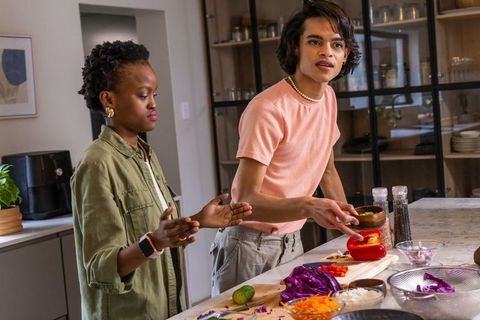 Diverse friends preparing colorful vegetable bowls on marble kitchen island for meal prep