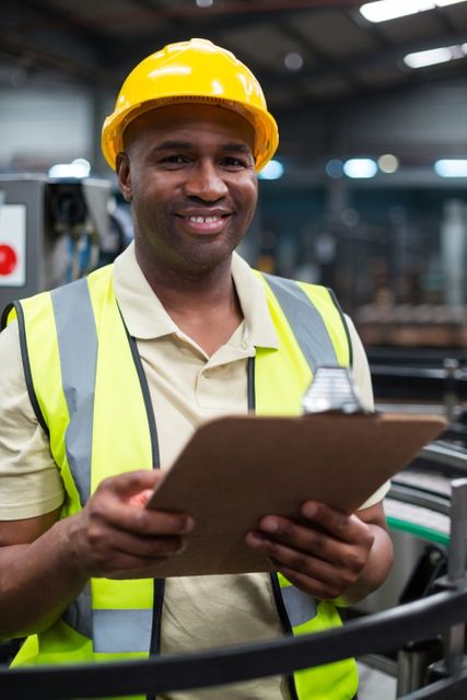 Portrait of smiling factory worker holding clipboard in factory