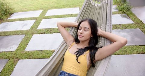Young Woman Relaxing in Hammock Outdoors in Tranquil Backyard