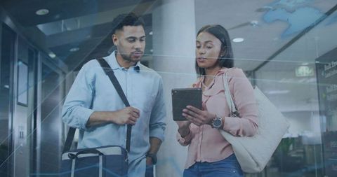 Young professionals consulting on tablet in airport concourse, planning business travel