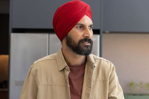 Indian Man in Modern Kitchen Glancing Sideways Near Refrigerator
