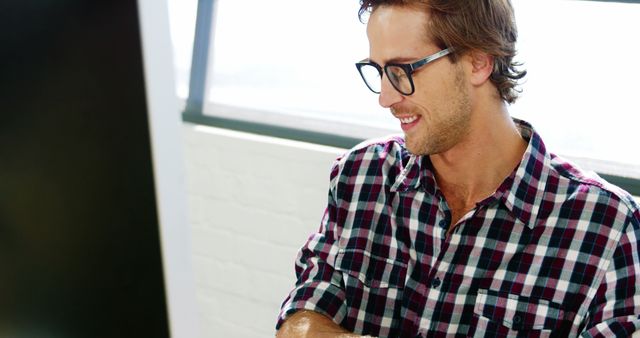 Smiling Man Wearing Plaid Shirt and Glasses Working in Office - Download Free Stock Images Pikwizard.com