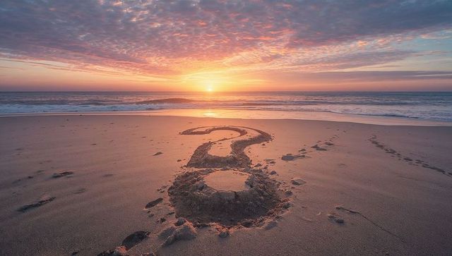 Sunrise on Beach with Question Mark in Sand Symbolizing Reflection