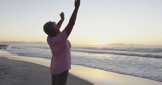 Biracial senior woman stretching at the beach. healthy outdoor leisure time by the sea.