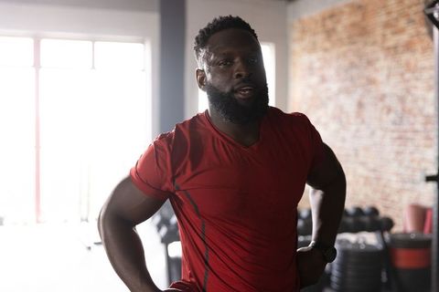 African american athlete pausing after strength workout in sunlit gym wearing red shirt