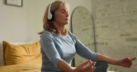Senior Woman Meditating In Tranquil Bedroom