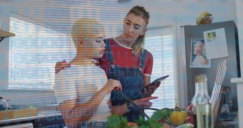 Couple using tablet while cooking together in bright kitchen with fresh vegetables
