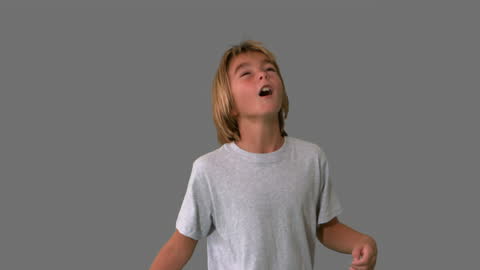 Excited Boy Playing Soccer on Grey Background in Slow Motion